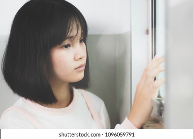 beautiful Asia woman ,teen,girl looking outside the window thinking to something with loneliness and sadness. - Shutterstock ID 1096059791