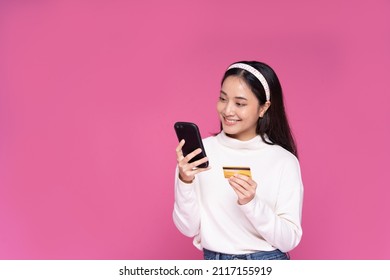 Beautiful Asia women smile use smartphone and credit card purchase online shopping and excited with success payment on isolated pink background - Shutterstock ID 2117155919