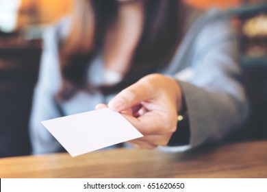 A Beautiful Asian Business Woman Holding And Giving Empty Business Card In Modern Loft Cafe