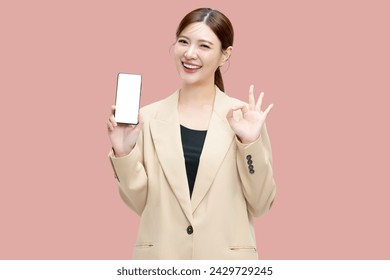 Beautiful Asian business woman showing smartphone mockup of blank screen with ok hand signal on pink background. - Powered by Shutterstock