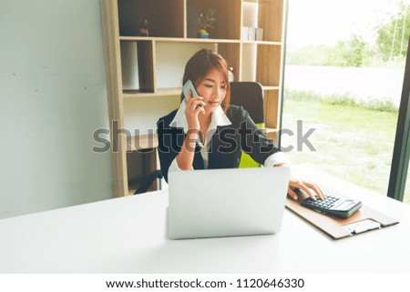 Beautiful asian business woman  talking on the cellphone working with laptop and calculator in office , Business and Office Concept.