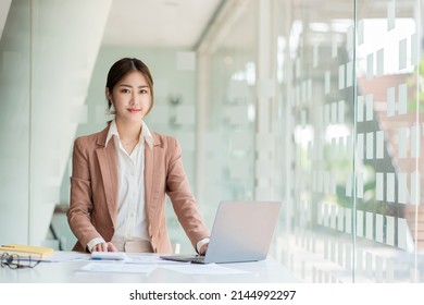 Beautiful Asian Businesswoman Analyzing Charts Using Laptop Calculator And Checkbook Happy Working Start Business Finance Calculating Accounting Concept In Office