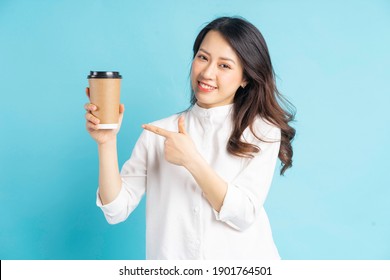 Beautiful Asian businesswoman holding paper coffee cup in her hand
