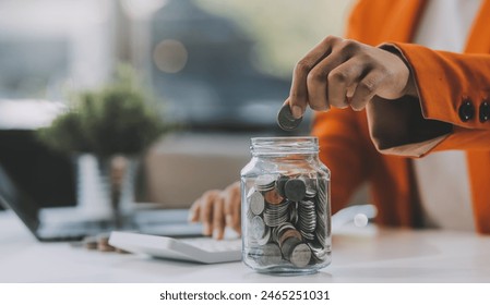 Beautiful Asian businesswoman insert coins in a pin piggy bank on the table. saving money, investment, currency concept - Powered by Shutterstock