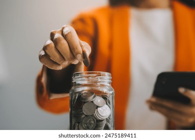 Beautiful Asian businesswoman insert coins in a pin piggy bank on the table. saving money, investment, currency concept