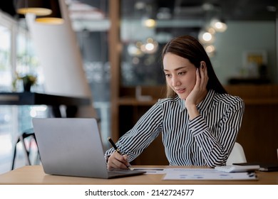 A beautiful Asian businesswoman sitting in her private office, she is checking company financial documents, she is a female executive of a startup company. Concept of financial management. - Shutterstock ID 2142724577