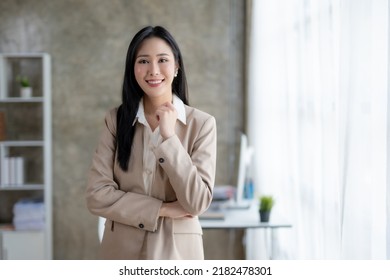 Beautiful Asian businesswoman standing with her arms crossed and confidently looking at the camera in the office.