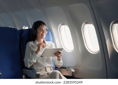 Beautiful Asian businesswoman working with digital tablet in aeroplane. working, travel, business concept - Powered by Shutterstock