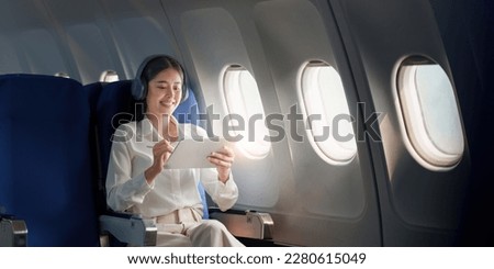 Beautiful Asian businesswoman working with digital tablet in aeroplane. working, travel, business concept