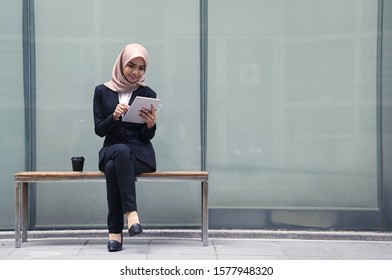 Beautiful Asian businesswomen wearing hijab using her tablet  at outdoor.                               