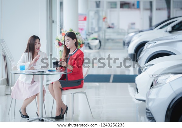 Beautiful Asian car salesman is communicating with\
customers. To buy a new\
car