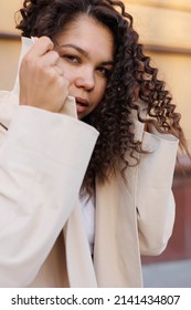 Beautiful Asian Caucasian Woman Covering Her Face With Beige Coat Outdoors In Street, Spring, Sun Shining. Woman Closed And Distrustful And Frightened	
