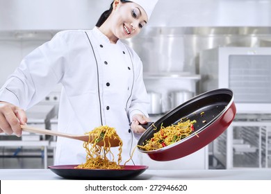 Beautiful asian chef cooks fried noodle in the kitchen - Powered by Shutterstock