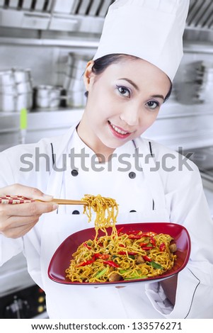 Beautiful Asian chef cooks fried noodle in kitchen