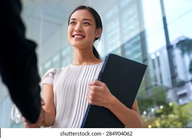 beautiful asian chinese business woman shaking hands in modern city work office