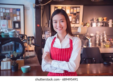 Beautiful asian coffee shop owner standing and smiles in her shop