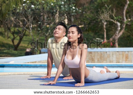 Beautiful Asian couple relaxing outdoors, they doing yoga on the mats on fresh air