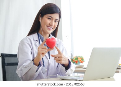 Beautiful Asian Doctor Have A Bright Smile Working In The Examination Room Hold A Pink Heart-shaped Ball. Cardiac Treatment Concepts, Medical Services In Hospitals