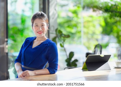 Beautiful Asian Entrepreneur.Lady In Big Office Window With Nature Background.Laptop On Table.Female Boss And Manager.Confident Chinese Person In Malaysia.Pretty Professional Working Woman.