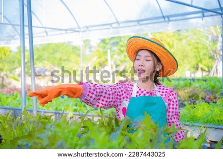 Beautiful asian farmer joyfully points out her organic vegetable garden, Smart farm.