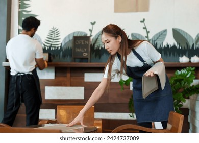 Beautiful Asian female barista cafe owner business woman Carrying placemats tablecloths after cleaning setting table Multiracial boyfriends packing things back Minimal style cafe small family business - Powered by Shutterstock