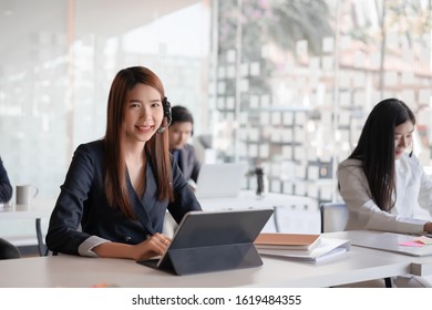 Beautiful asian female call center agent in headset consulting client. Customer service team support concept - Shutterstock ID 1619484355