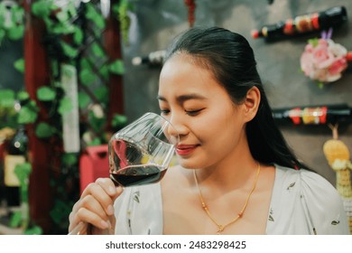 Beautiful asian female customer who likes drink wine for health : Portrait happy asian woman holding glass red wine, smelling the aroma judging the good taste and tasting good mood in a wine shop. - Powered by Shutterstock