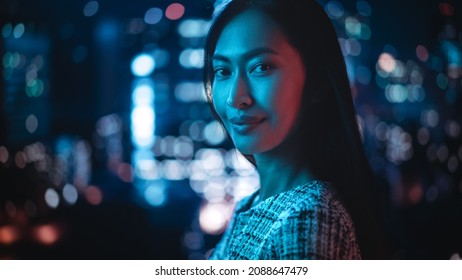 Beautiful Asian Female Portrait Standing On City Street With Neon Lights Late In The Evening. Authentic Adult Confident Woman Posing For Camera, Smiling In The Night On Downtown Business Street.