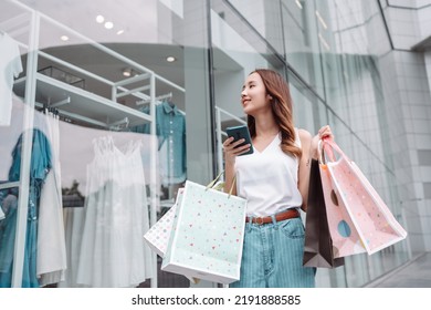 Beautiful asian female woman girl use smartphone and holding shopping bags, Walk enjoy smiling while doing shopping outside of department store malls window outdoors fashion lifestyle