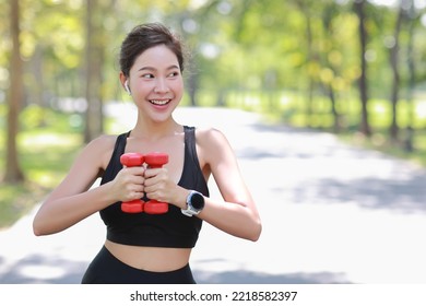 Beautiful asian fitness female sportswoman lifting dumbbell weight training after finish morning run outdoor. Happy smiling athlete woman excercising under the tree in the park while staring away - Shutterstock ID 2218582397