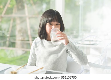 Beautiful Asian Girl Drinking  Glass Of Water In A Restaurant