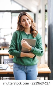 Beautiful Asian Girl Enjoys Coffee While Working In A Coffee Shop On Laptop Connected To Public Wifi. Stylish College Student Studying Online While Spending Free Time In The Park.