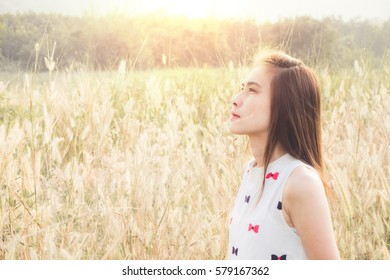 Beautiful Asian Girl In Golden Meadow. Young Woman Looking Up Into The Sky