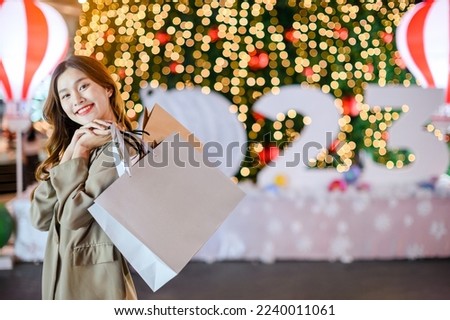 Beautiful asian girl hold shopping bags on christmas tree bokeh light background at night, happy new year vibes concept