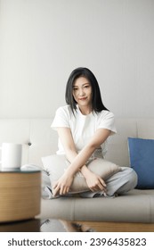 Beautiful Asian girl resting on sofa in living room - Shutterstock ID 2396435823