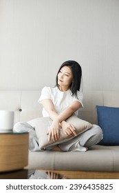 Beautiful Asian girl resting on sofa in living room - Shutterstock ID 2396435825
