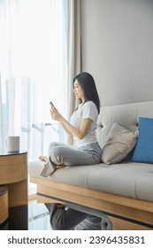 Beautiful Asian girl resting on sofa in living room - Shutterstock ID 2396435831