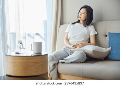Beautiful Asian girl resting on sofa in living room - Shutterstock ID 2396435837