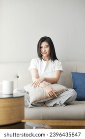 Beautiful Asian girl resting on sofa in living room - Shutterstock ID 2396435847