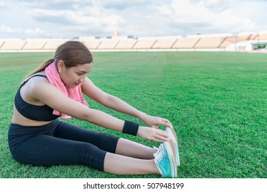 Beautiful asian girl Stretch seating on the lawn in the soccer field,excercise,warm body - Powered by Shutterstock