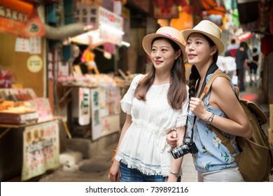 beautiful Asian girls visiting and walking on Jiufen old street pedlar of Taipei Taiwan holiday travel, vendors around.