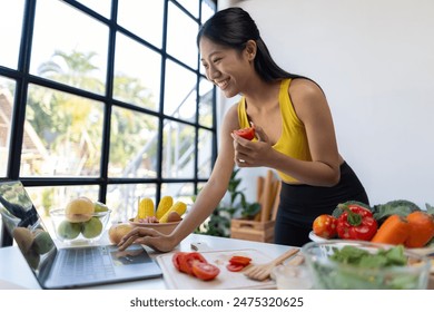 Beautiful Asian influencer woman making vegetable salad at home. Fitness influencer on social media online showing tomato for healthy eating. Vlogging and blogging online, weight loss and dieting. - Powered by Shutterstock