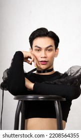 beautiful Asian man posing with the chair while wearing a black costume and makeup inside the white studio - Shutterstock ID 2208564355