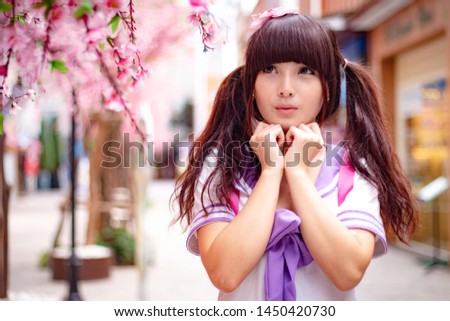 Beautiful Asian model in Japanese student uniform with cherry blossom flower 