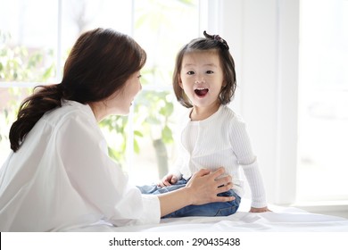 Beautiful Asian Mom And Her Cute Daughter Kissing With Love While Looking At Each Other
