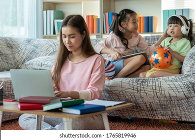 A Beautiful Asian Mother Busy Working While Looking After And Teaching Her Children On A Laptop Computer At Home