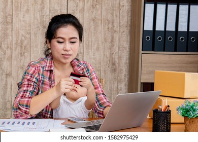 Beautiful Asian Mother Woman Taking Care Baby Multi Task Working At Home Using Laptop, Smartphone Packing Products Cardboard, Small Business Startup Entrepreneur, Freelance Lifestyle Shopping Online