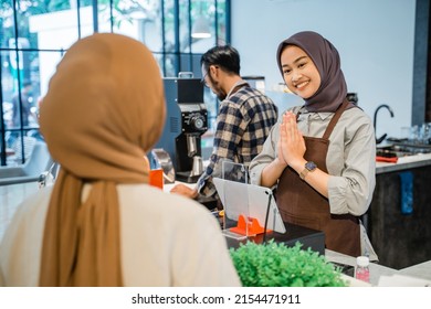 Beautiful Asian Muslim Cafe Worker Welcoming Customer At Her Shop