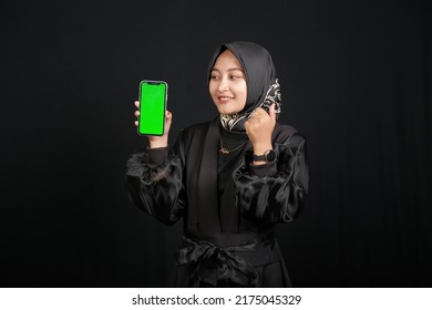 Beautiful Asian Muslim Girl Holding Green Screen Mobile Phone On Black Background