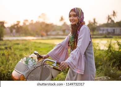 beautiful asian muslim woman wearing hijab riding a bike in neighbourhood - Powered by Shutterstock